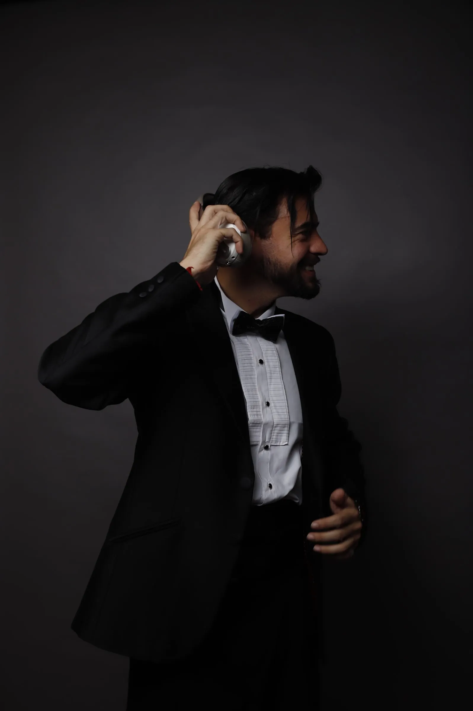 Aaron Benchimol in a tuxedo, smiling as he listens through his DJ headphones