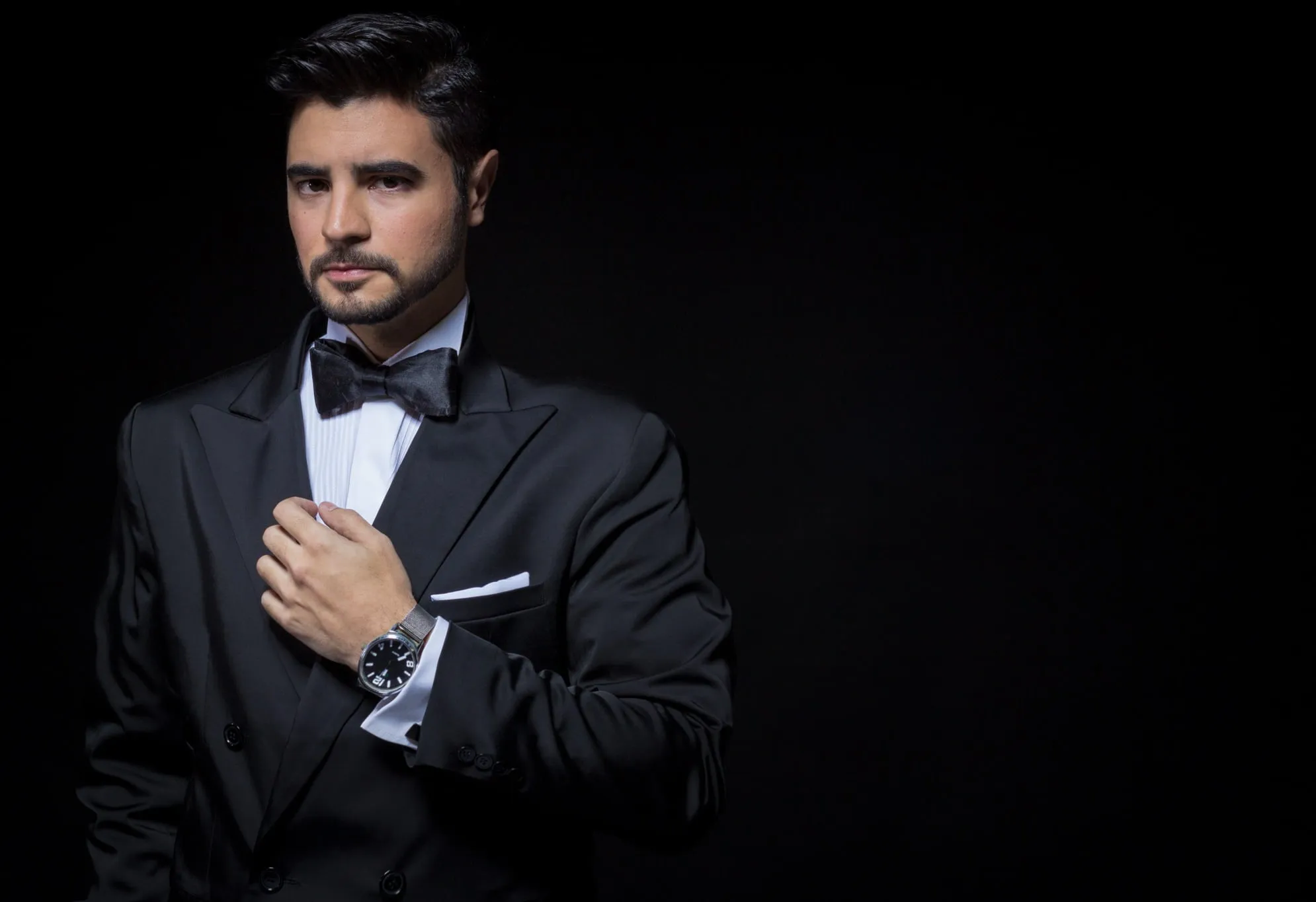 Portrait of Aaron Benchimol in a tuxedo and bow tie, adjusting his jacket
